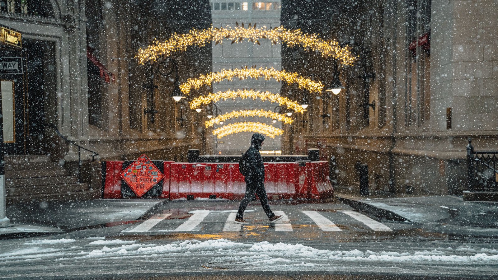 Una strada di New York sotto la neve, con le luci di Natale sopra la carreggiata